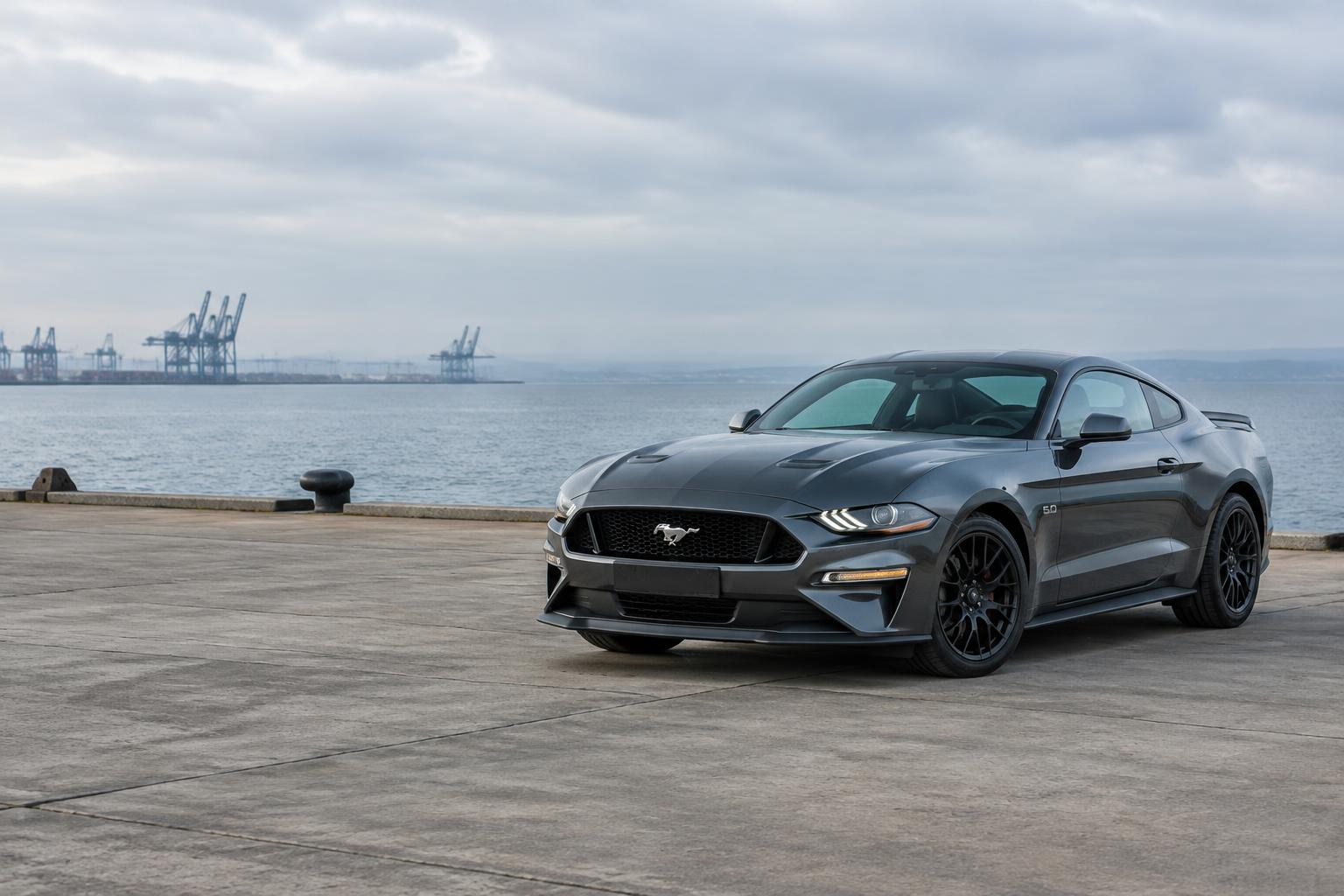 Ford Mustang grise face à l’océan sur un quai